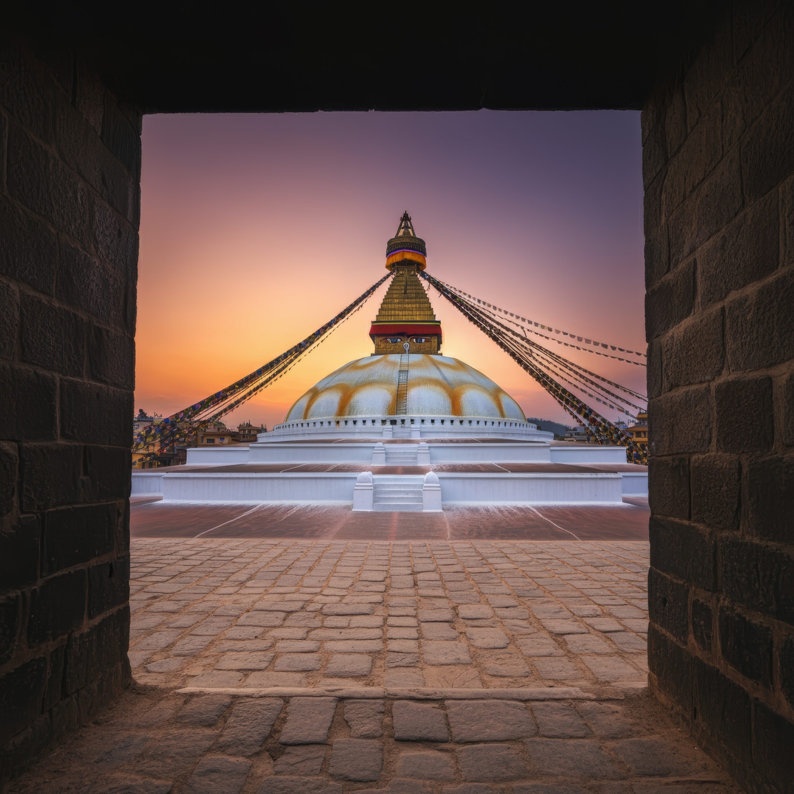 View of the Boudhanath Stupa in Kathmandu Nepal against a blue sky in warm evening light.